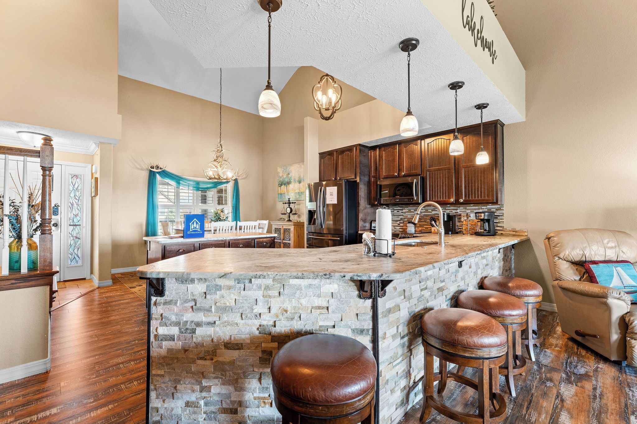 A spacious kitchen with a large island, wooden cabinets, and pendant lighting.