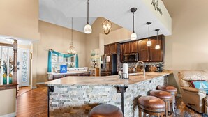 A spacious kitchen with a large island, wooden cabinets, and pendant lighting. - Table Rock View Penthouse with Sun Room, Luxury Decor, Free Tickets & Prime Location (Branson)