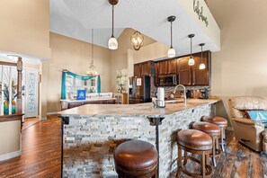A spacious kitchen with a large island, wooden cabinets, and pendant lighting.