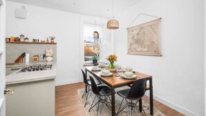 A modern kitchen with a gas stove, a wooden dining table set for four, and a hanging light fixture. - Regal Residence - Metropolitan Luxury (Broughty Ferry, Dundee)