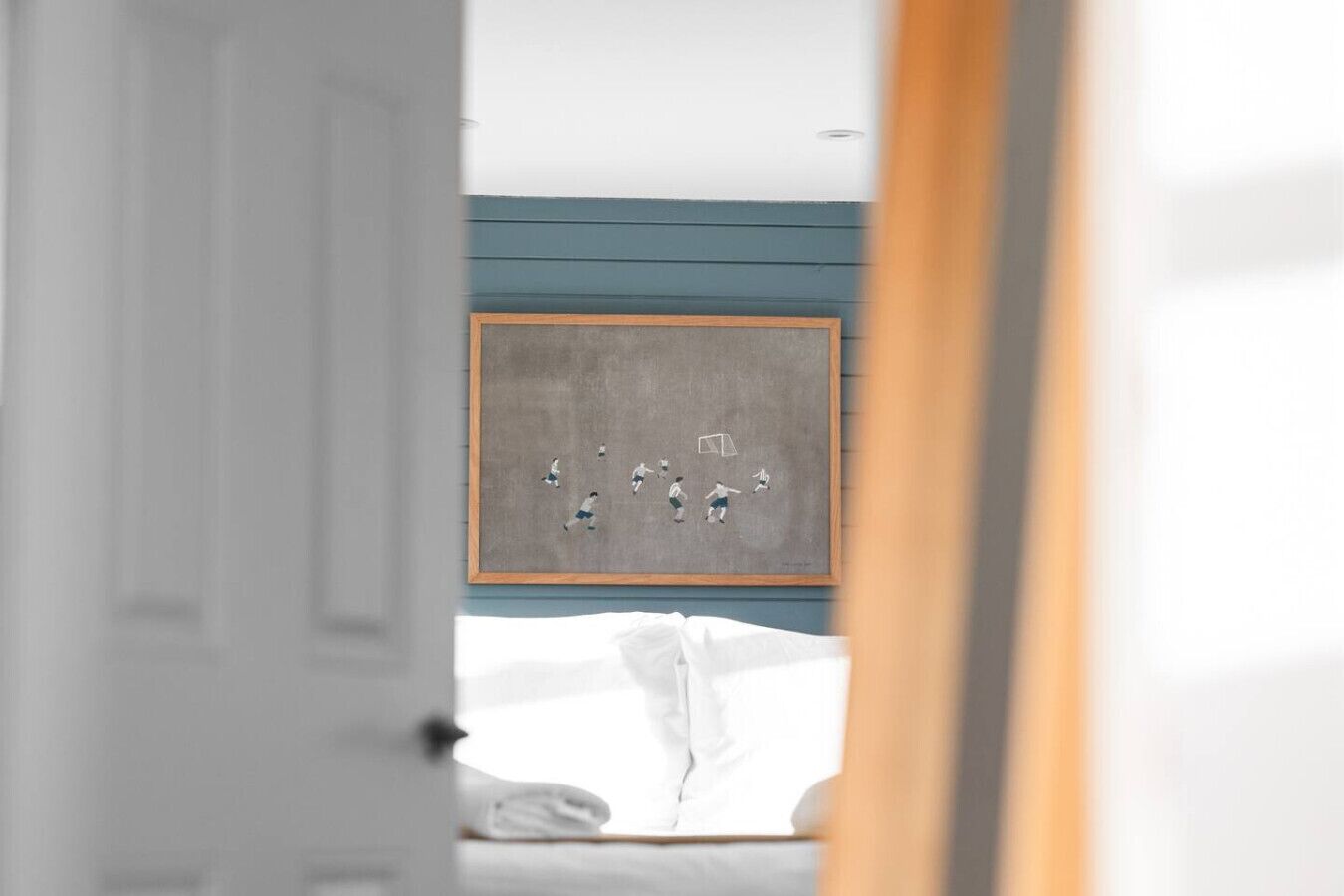 Un dormitorio con una cama, una obra de arte enmarcada en la pared y una puerta que da a otra habitación.