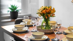 A dining table set with plates, bowls, and wine glasses, with a vase of flowers in the center. - Regal Residence - Metropolitan Luxury (Broughty Ferry, Dundee)