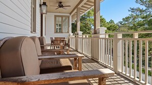A covered porch with outdoor seating, a ceiling fan, and a view of the surrounding greenery. - Dejarnette Cottage w/Private Courtyard & Pool | 30A Rosemary Beach | My Beach Getaways (Rosemary Beach)