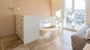 A room with a sliding glass door to a balcony, a white cabinet, and a beige wall.