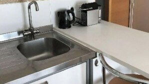 A kitchen with a microwave, sink, and a coffee maker.