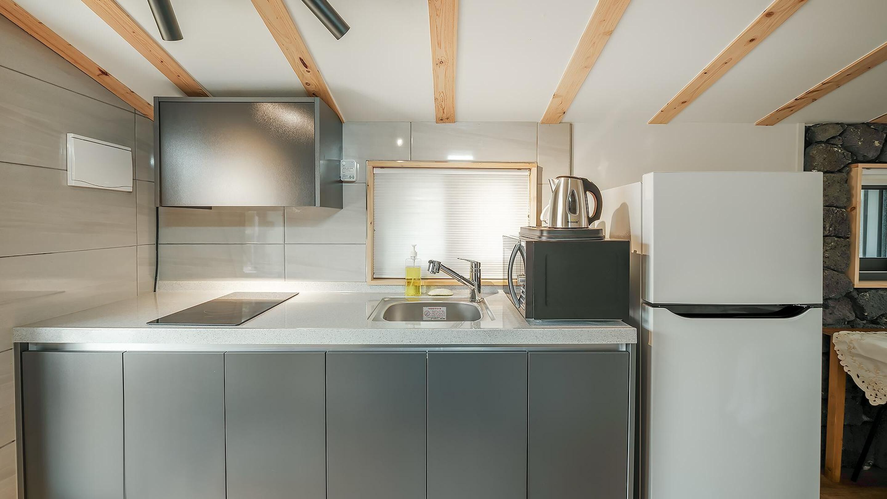 Una cocina moderna con un lavamanos de acero inoxidable, una tetera y un refrigerador.