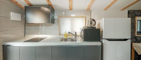Una cocina moderna con un lavamanos de acero inoxidable, una tetera y un refrigerador.