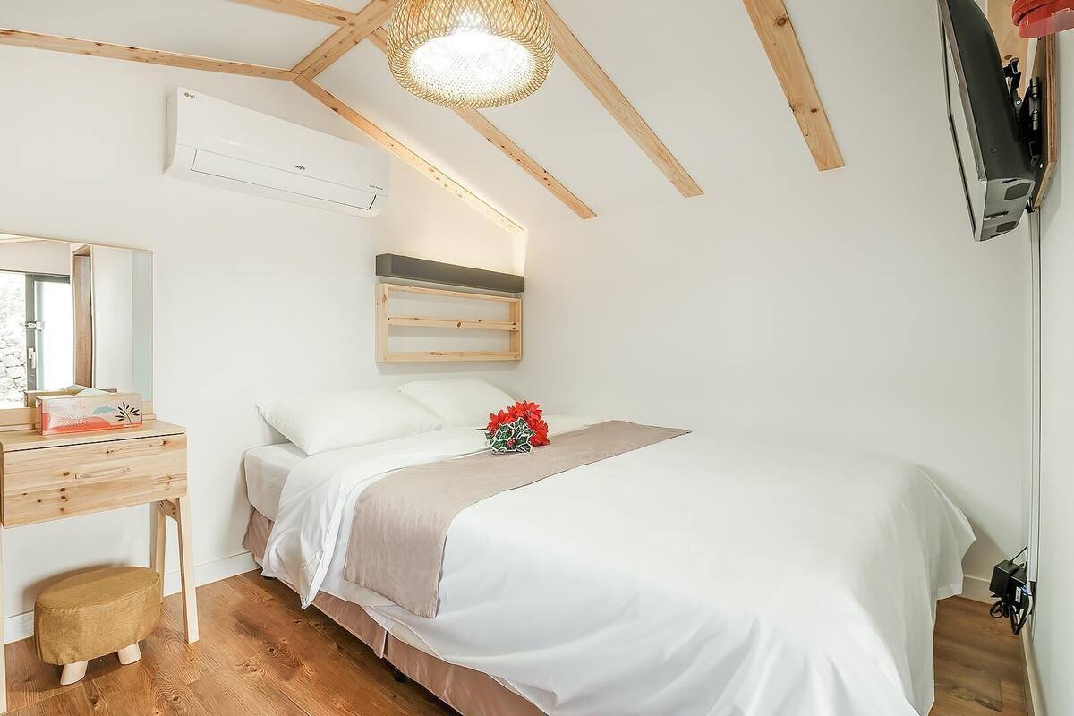 Ein Schlafzimmer mit einem Bett, einem Schminktisch, einem Spiegel, einer Wandklimaanlage und einer Deckenleuchte.