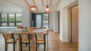 A dining area with a wooden table and chairs, two pendant lights, and a view through a glass door to the outdoors. - Pyeongdae Moons Stay Pension (Jeju City)