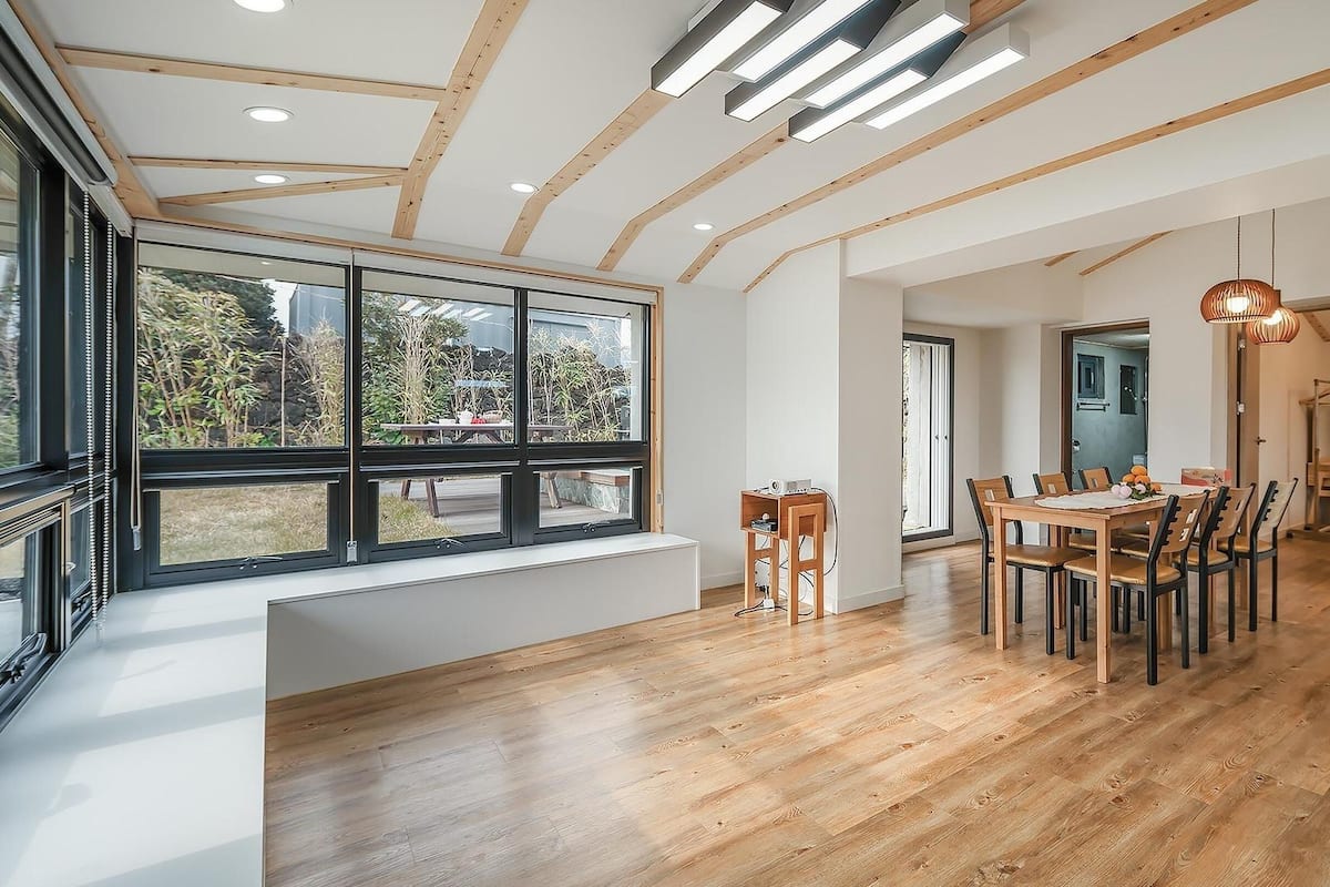 Ein moderner Essbereich mit Holzboden, einem großen Fenster und einem Esstisch mit Stühlen.