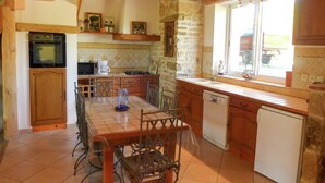 A kitchen with a stone wall, wooden cabinets, a tiled backsplash, and a window overlooking a truck. - Villa in Conilhac with Private Terrace (Conilhac-De-La-Montagne)