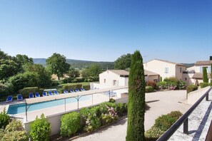 A pool area with lounge chairs, a building with a tiled roof, and a clear sky. - Sunny Stay in Lavender Land (BONNIEUX)