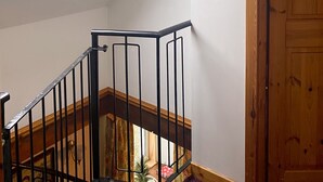 A room with a skylight, a wooden door, and a staircase with black railings.