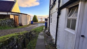 A narrow alleyway with stone walls and a grassy path.