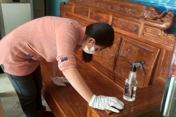 A person cleaning a wooden headboard with a spray bottle. - Xujingyuan Smart Hotel (Xuwen Dengyunta People's Government Branch) (Xuwen)