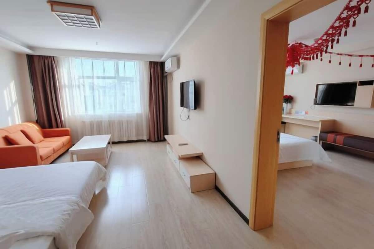 A hotel room with two beds, a sofa, a TV, and a small table.