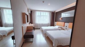 Une chambre d’hôtel avec deux lits, un bureau, une banquette et une grande fenêtre.