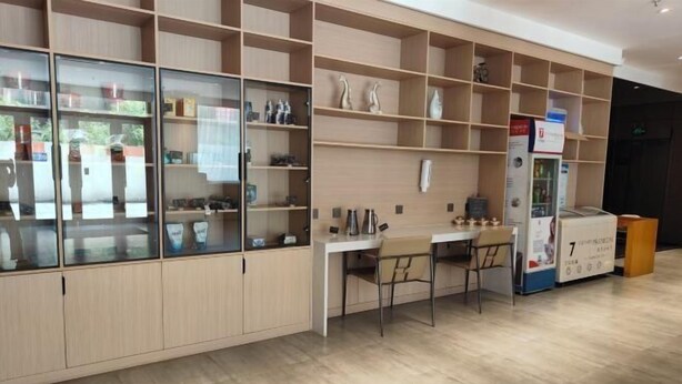 Un intérieur moderne avec des étagères en bois, un bureau blanc, deux chaises et un distributeur automatique.
