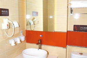 A hotel bathroom with a sink, mirror, towel rack, and a sign indicating a caution for slippery floor. - Kela Star Hotel (Shenyang Sujiatun Exhibition Center) (Shenyang)