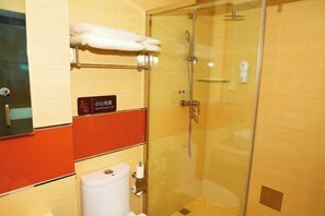 A hotel bathroom with a glass-enclosed shower, a toilet, and a towel rack.