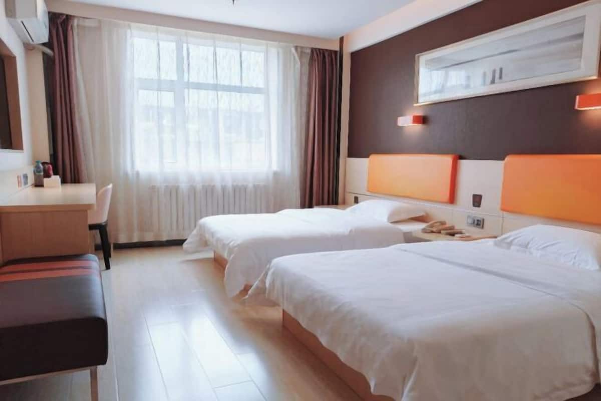 A hotel room with two beds, a desk, and a chair.
