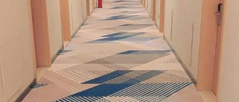 A long, narrow hallway with patterned flooring and doors on both sides.