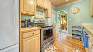 A kitchen with wooden cabinets, a stainless steel oven, and a clock on the wall.