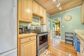 A kitchen with wooden cabinets, a stainless steel oven, and a clock on the wall. - Escape to Lookout Lodge in Saugatuck, a 3-bedroom retreat with water views. (Saugatuck)