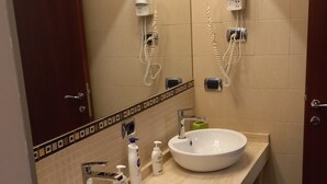 A bathroom with two sinks, a mirror, and a hairdryer mounted on the wall. - Stefano House Apartment Trevi Fountain  (Roma)