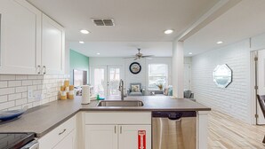 Una cocina moderna con armarios blancos, lavavajillas y ventilador de techo.