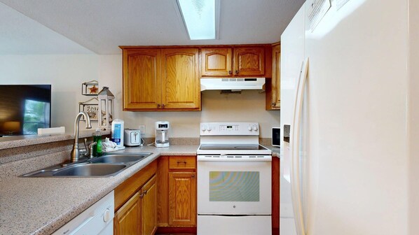 Una cocina compacta con armarios de madera, horno empotrado, microondas y pileta.