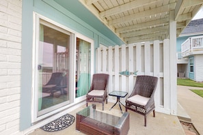 Relax in a serene outdoor space with a glass-top coffee table and two comfortable wicker chairs.