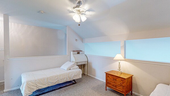 A bedroom with a bed, a nightstand, a lamp, a ceiling fan, and a window.