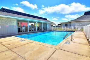 Piscina com área de estar coberta e deck cercado.