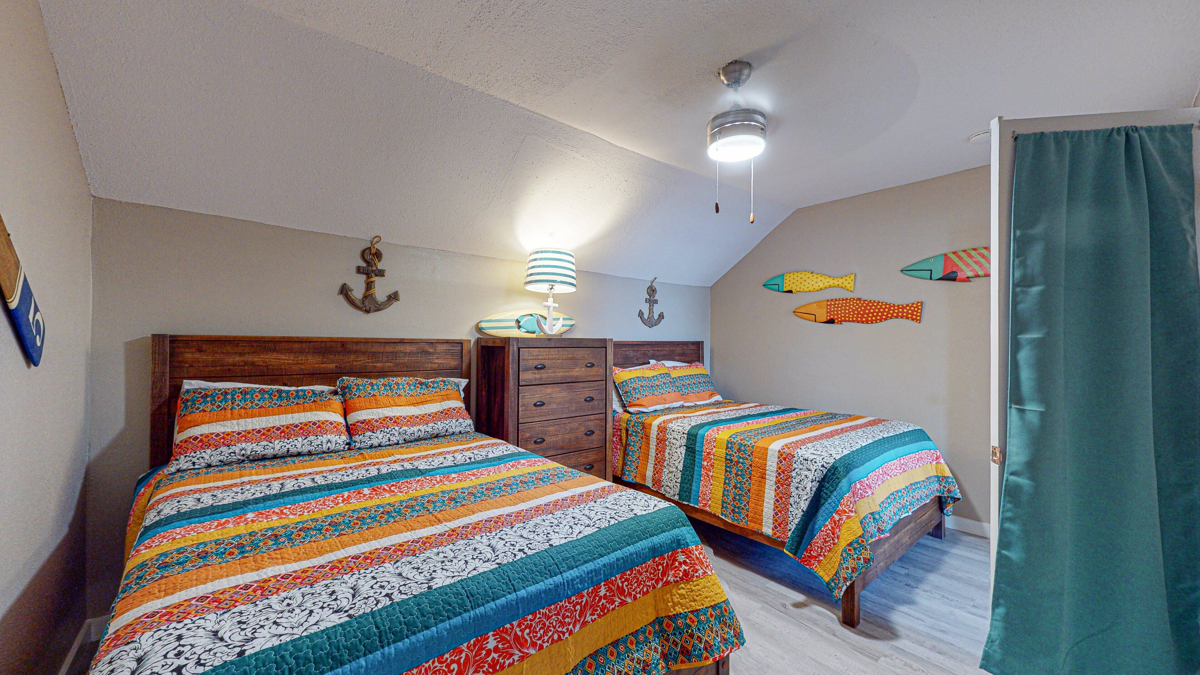 A bedroom with two beds, a ceiling fan, and decorative fish on the wall.