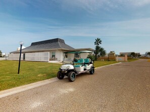 En golfbil parkerad på en bostadsgata med ett hus i bakgrunden.