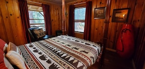 A wooden cabin room with a bed, a chair, and a red heater. - Cottage #3 near a Creek & Pond on Mt. Lassen (Shingletown)