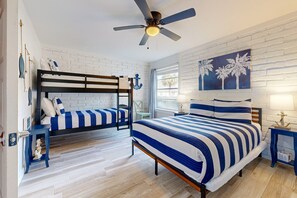 Ein Schlafzimmer mit einem Etagenbett, einem Einzelbett, einem Deckenventilator, einem Fenster mit Blick und einer Wand mit einem Palmenbild.