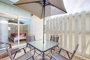 Eine Terrasse im Freien mit Tisch und Stühlen, einem großen Sonnenschirm und einem weißen Zaun.