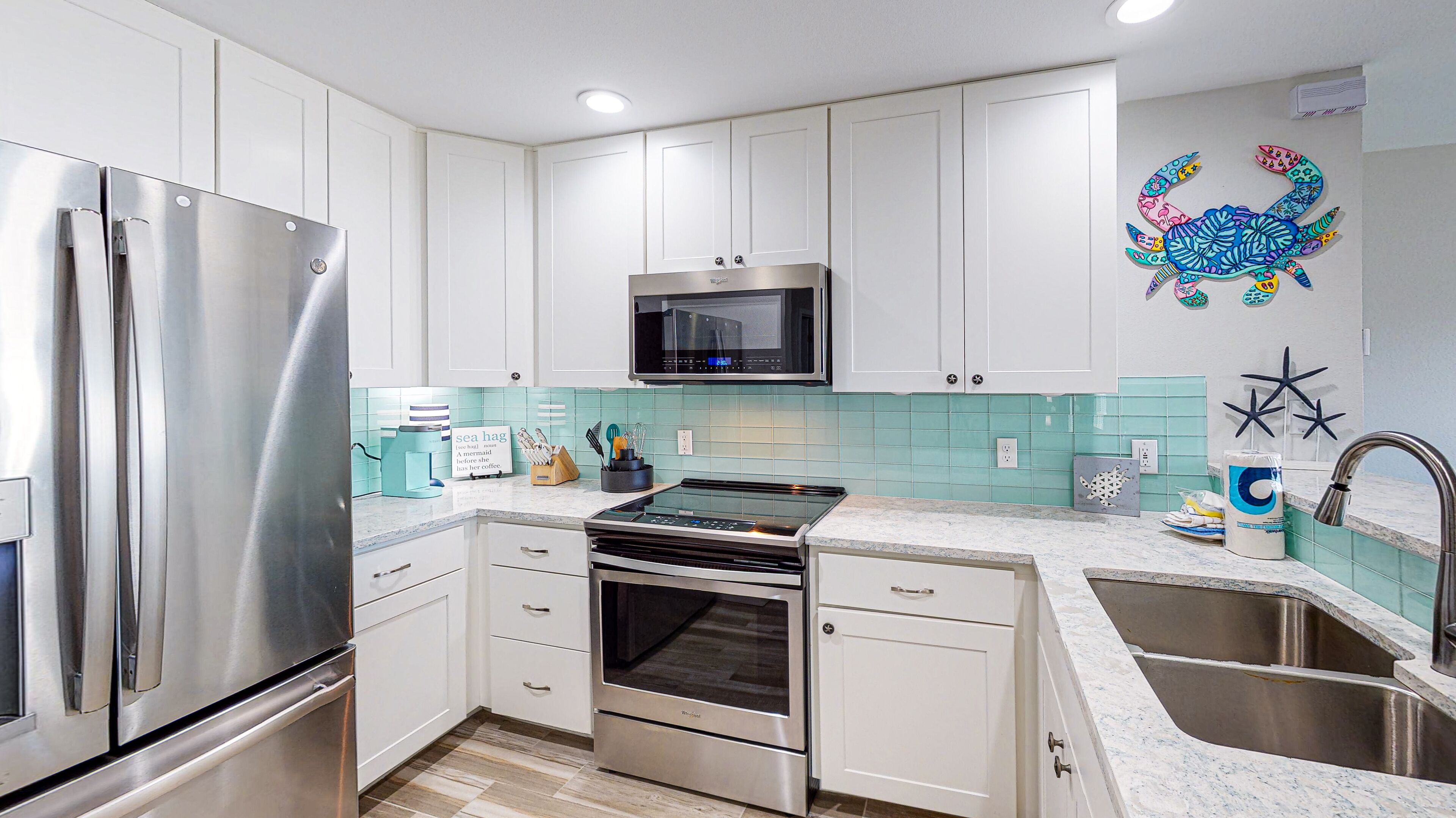 Una cocina moderna con electrodomésticos de acero inoxidable, armarios blancos, un microondas y una placa vitrocerámica.