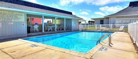Ein Pool mit überdachter Sitzgelegenheit und umzäunter Liegefläche.