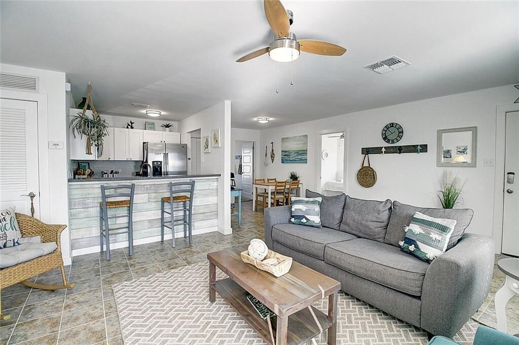 A modern living room with a grey sofa, wooden coffee table, and a ceiling fan.