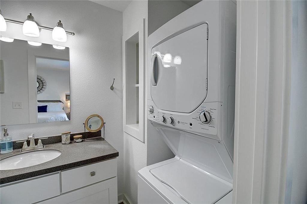 Un baño con lavabo, espejo y lavadora integrada.