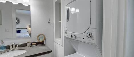 Un baño con lavabo, espejo y lavadora integrada.
