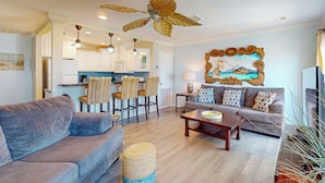 A spacious living area with a sofa, a coffee table, and a dining area with chairs. - Second Floor Condo, Pet Friendly, Shared Pool and Grill, Boardwalk (Port Aransas)