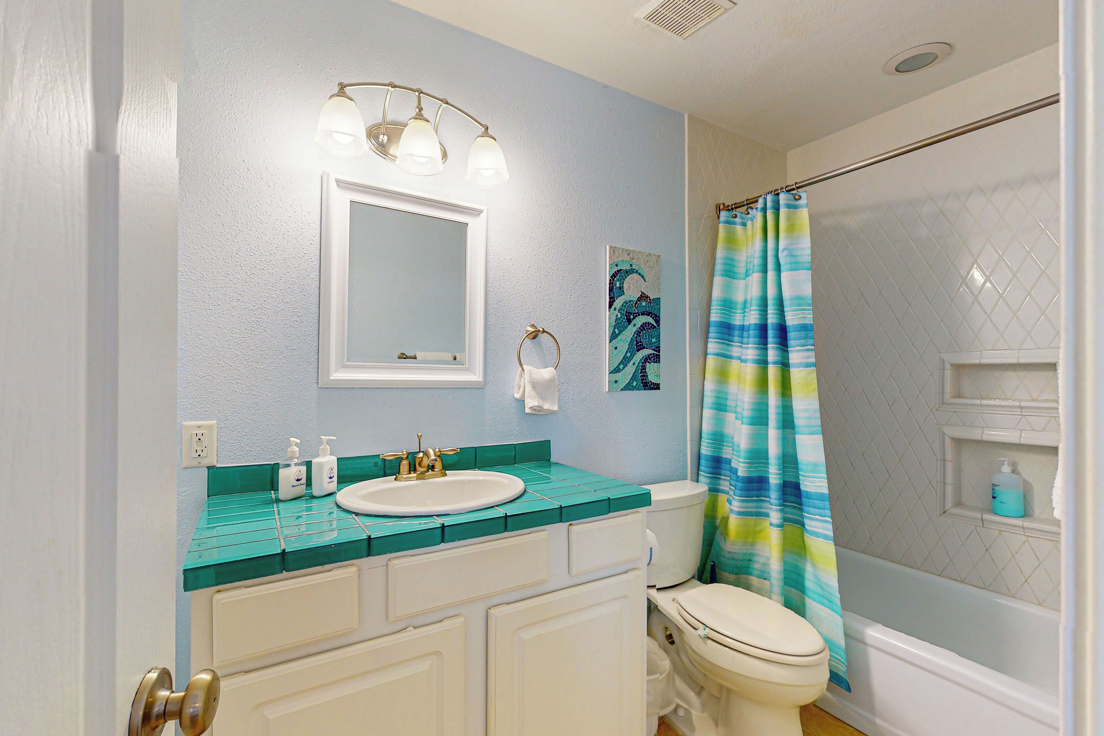 A bathroom with a white sink, a mirror, a toilet, and a shower curtain.