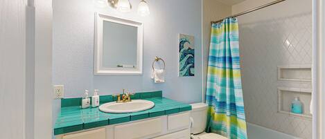 A bathroom with a white sink, a mirror, a toilet, and a shower curtain.