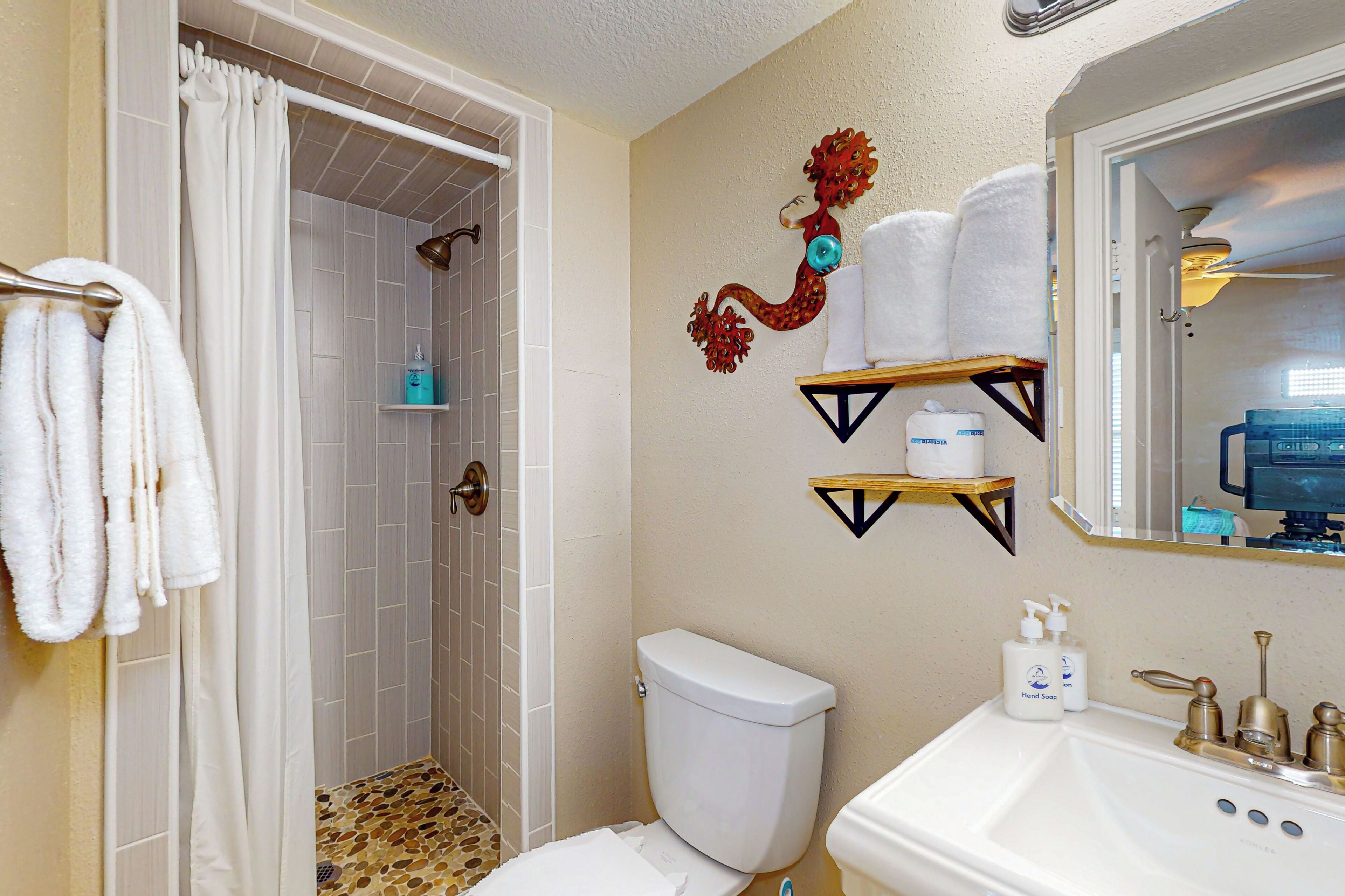 Un baño con ducha, inodoro, lavamanos y toalleros.