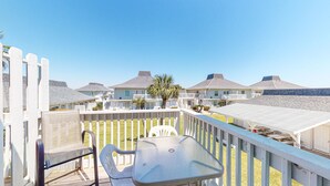 Un balcón con una mesa y sillas, con vista a una hilera de casas de playa con balcones y palmeras.
