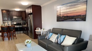Un salon moderne avec un canapé en cuir gris, une table basse blanche et un coin repas avec des chaises en bois.